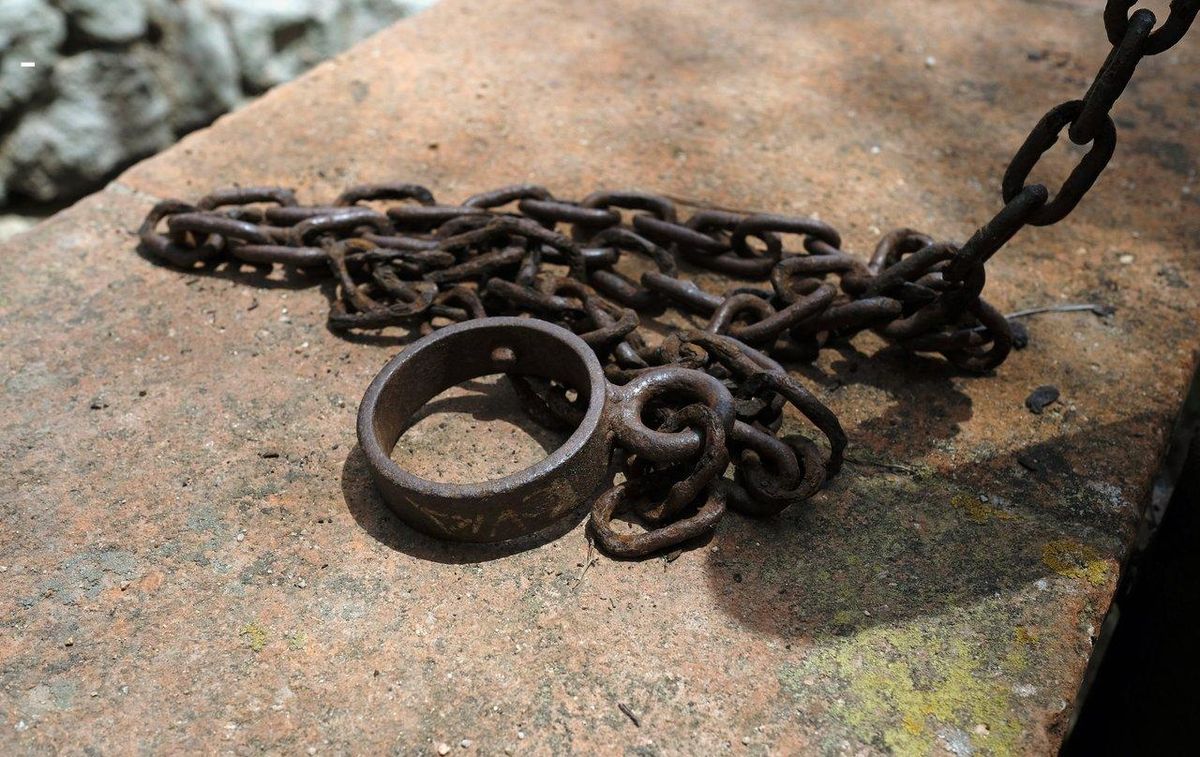 Décor rustique médiéval avec chaîne en métal attachée au mur pour une ambiance bondage médiévale authentique.