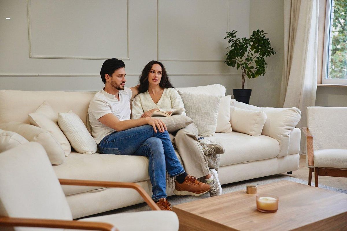 Un couple intime dans un salon chaleureux, partageant un moment de complicité sur un canapé confortable.