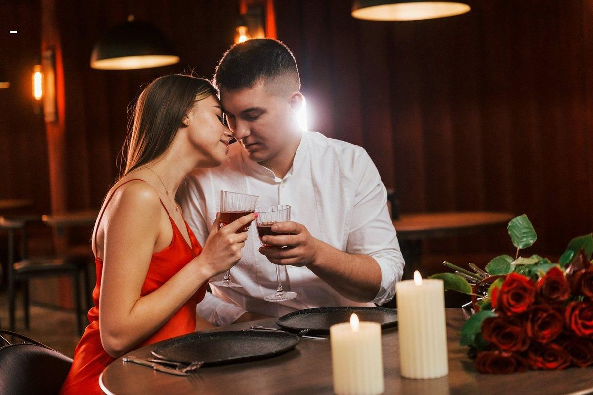Un couple romantique en candlelight, partageant un moment doux et sensuel dans une ambiance tamisée.