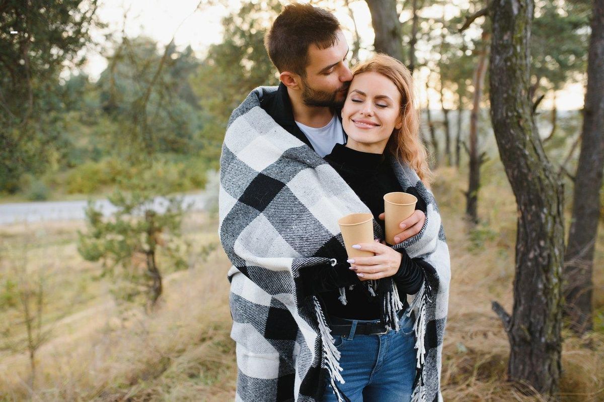 Un couple se câline tendrement sous un plaid, symbole d’un aftercare chaleureux après une séance de bondage.