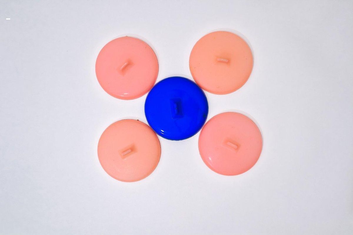 Une sélection de decorative anal plugs en plastique coloré, présentés sur un tissu de velours pour une touche esthétique.