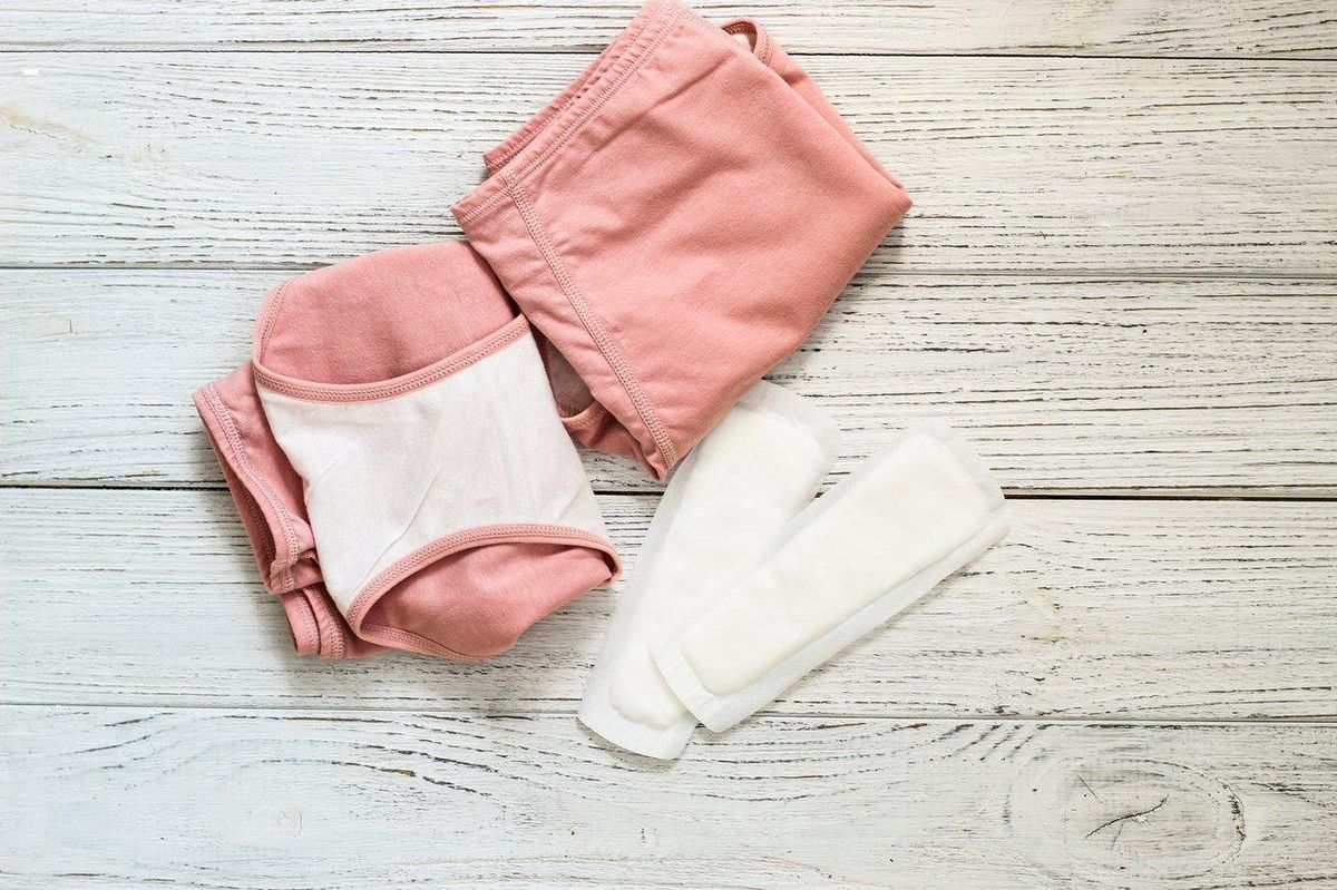 Vue détaillée des couches multicouches d'une lingerie menstruelle absorbante avec système d'agrafes latérales pour une absorption optimale.