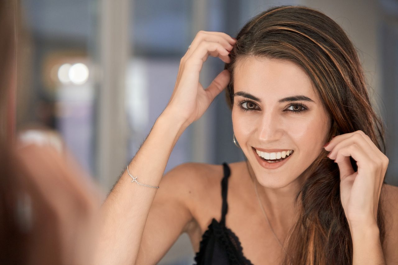 Femme élégante d'une trentaine d'années aux cheveux bruns, regard assuré et sourire léger, portrait en intérieur tamisé aux tons prune